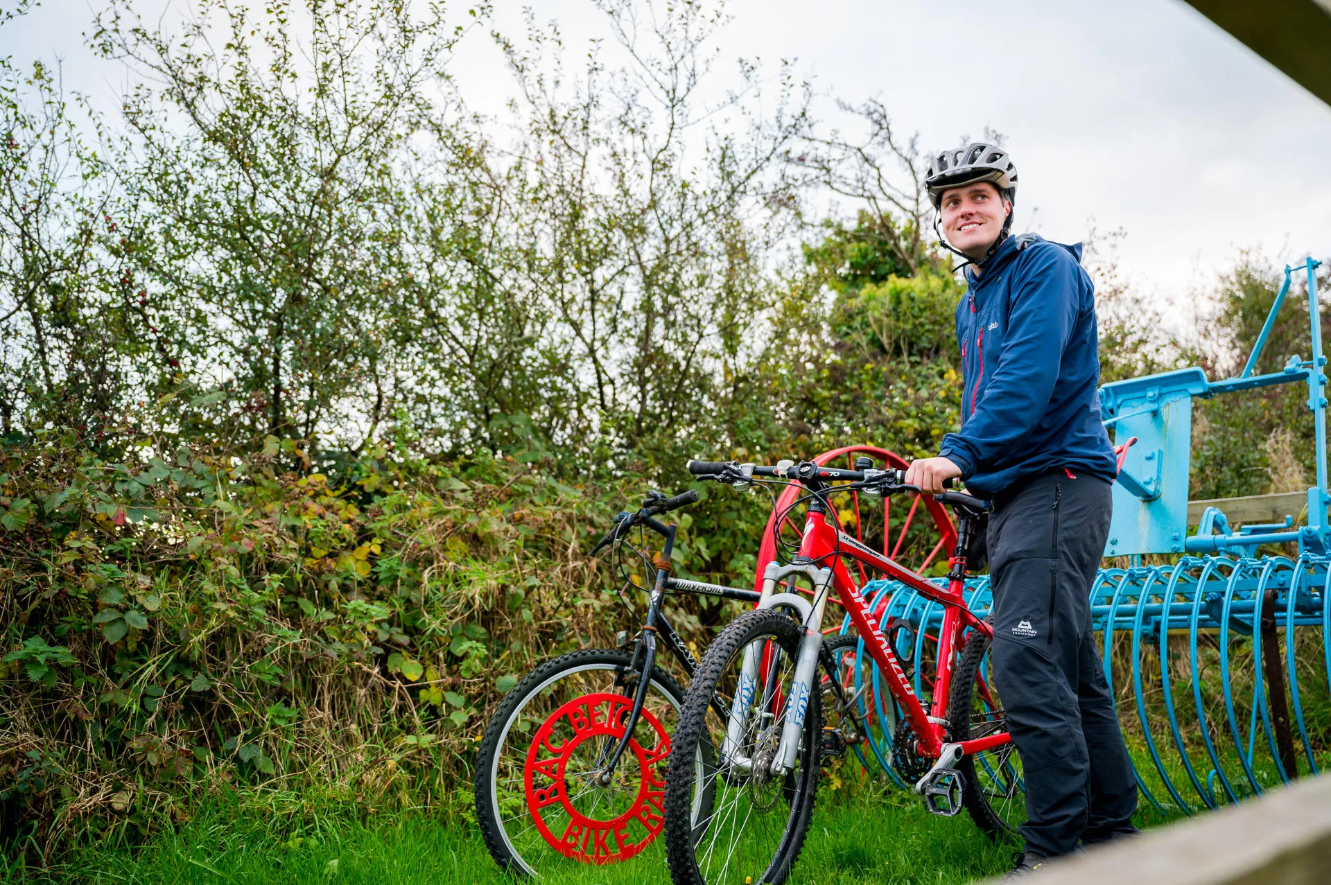 Cyclists next to blue and red cycle rack at Cors Ddygai Part of NCS 566.