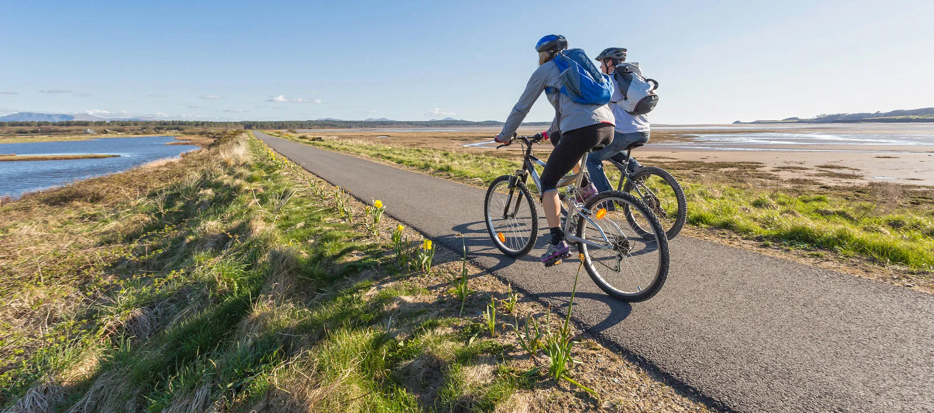 Two Cyclists enjoying the peace and sunshine on the off-road Malltraeth Cob with sea either side