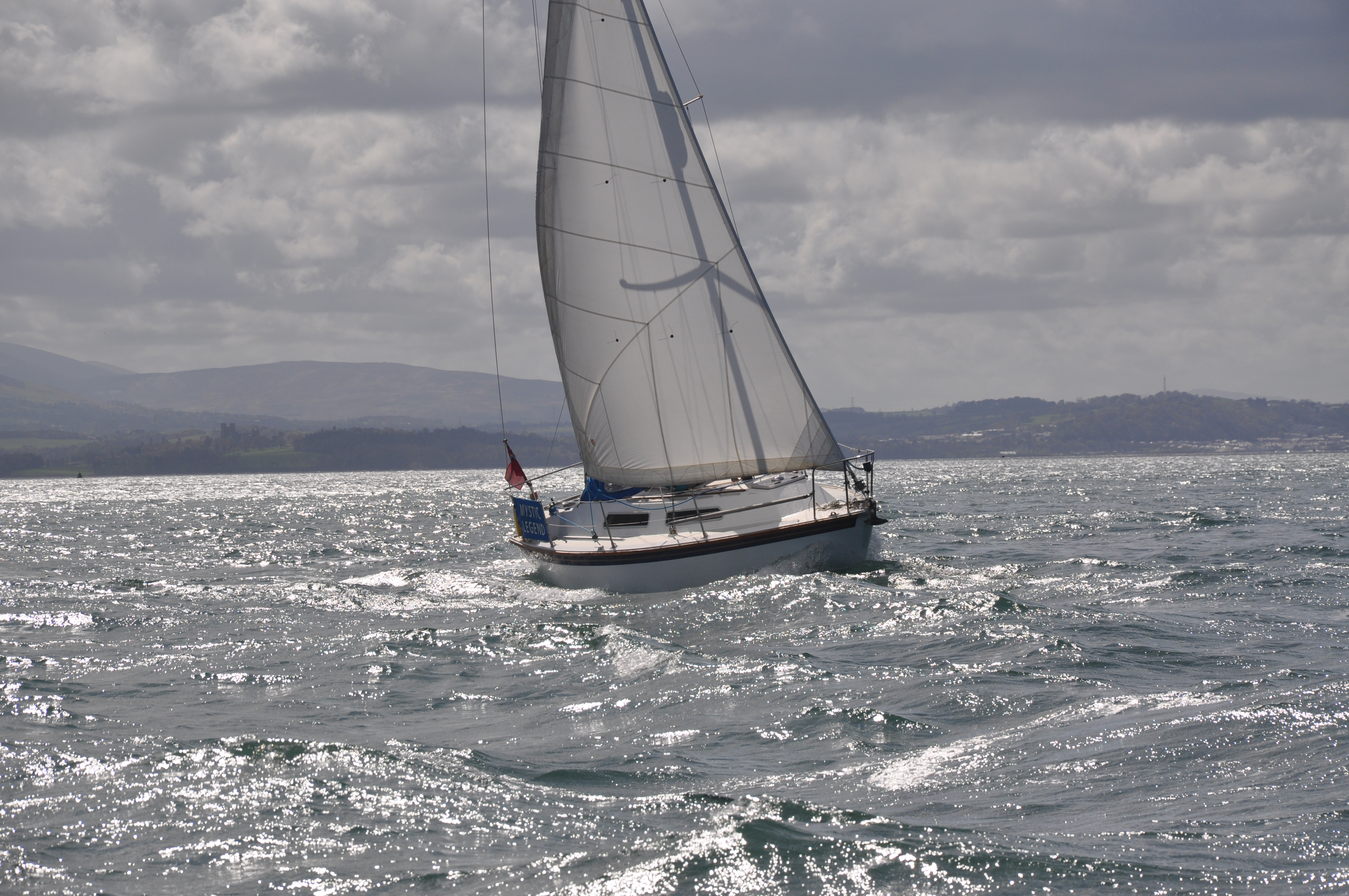 Sailing boat in full Sail close hauled in slight swell going round puffin island.