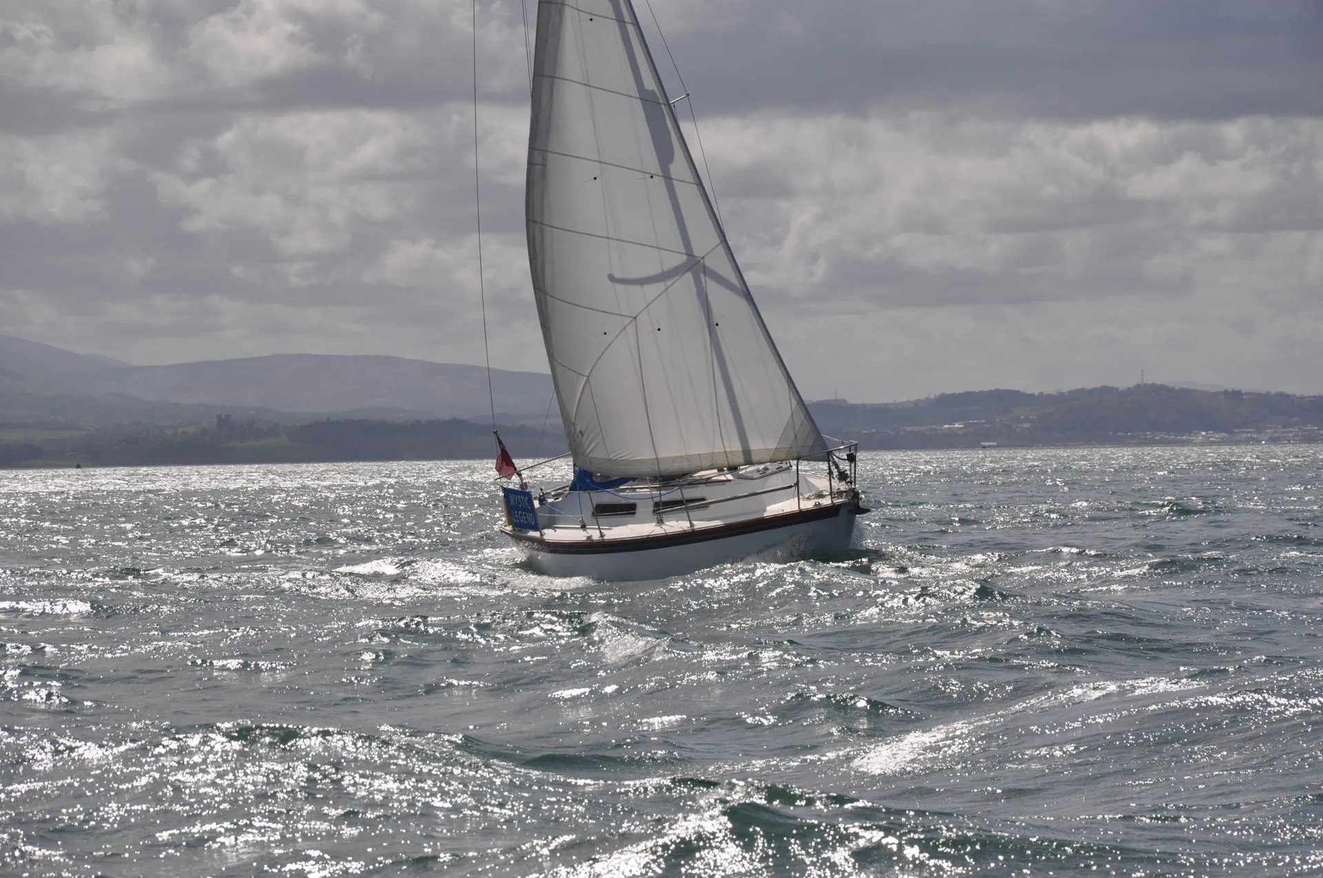 Sailing boat in full Sail close hauled in slight swell going round puffin island.