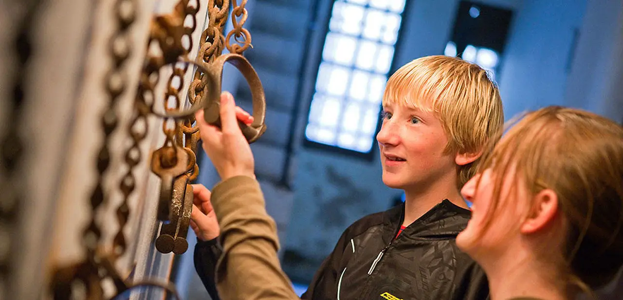 Two young people looking in excitement and touching the chains at the Gaol