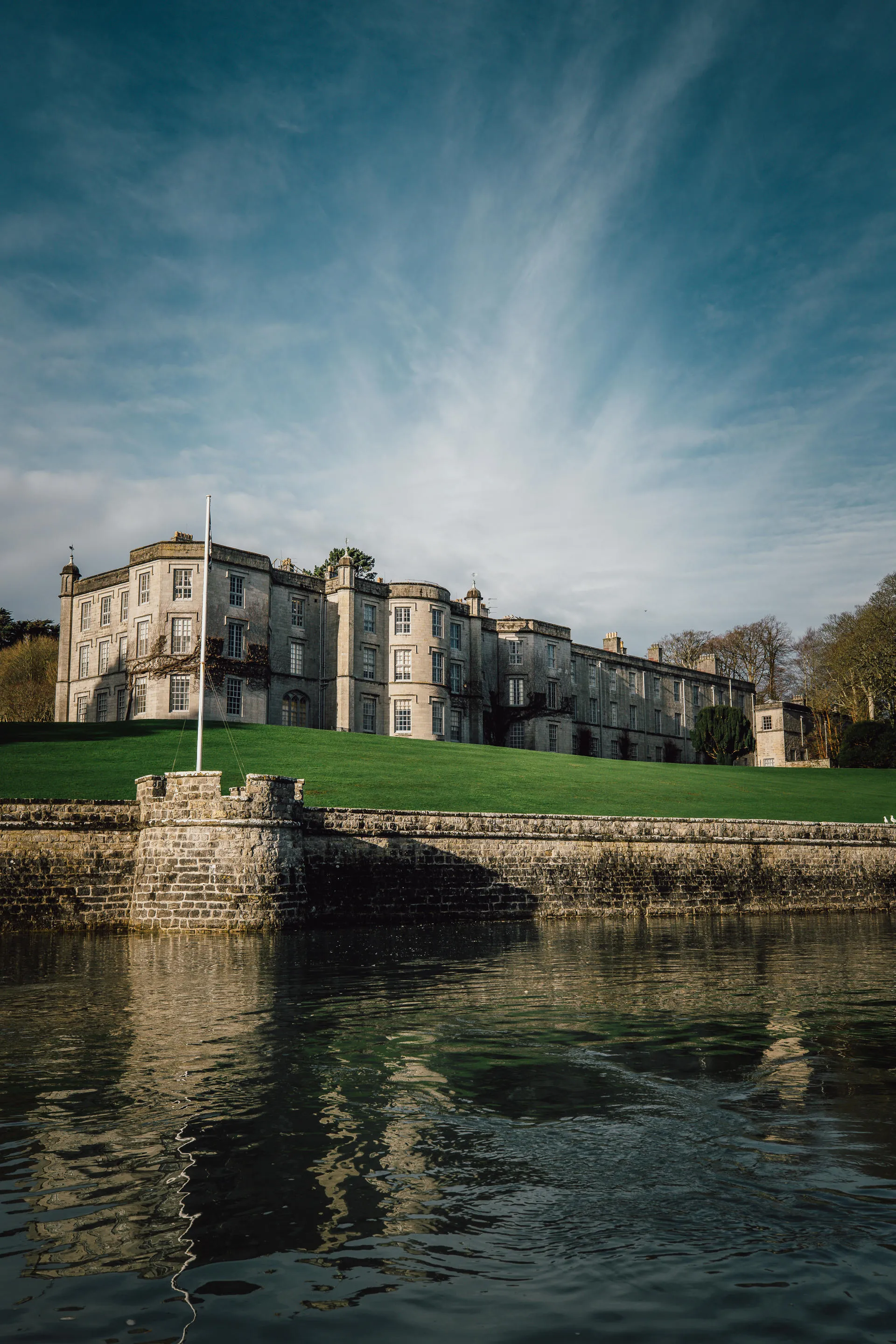 Looking up at Plas Newydd from Menai Strait with wispy clouds floating overhead
