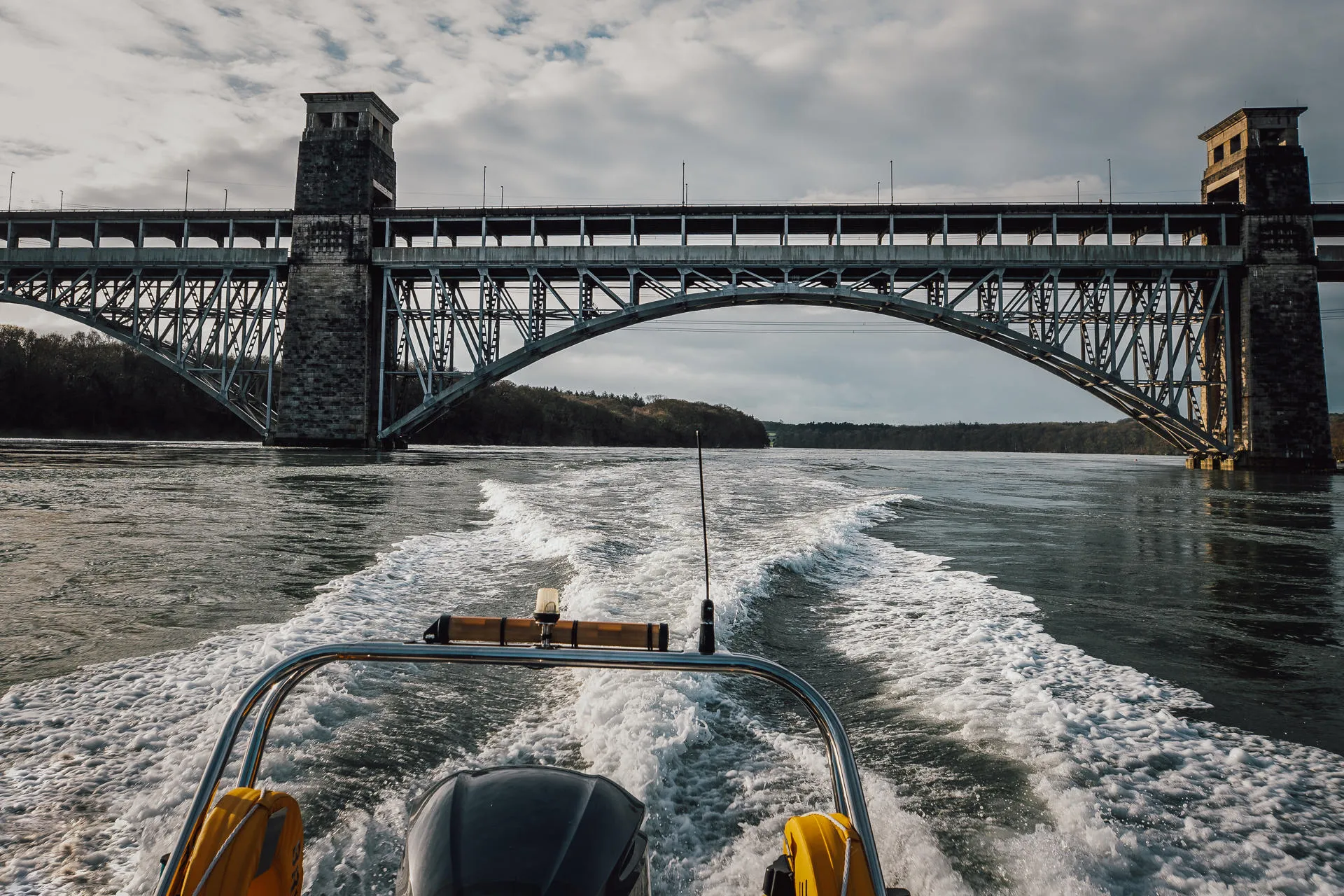 Raft of RIb going under Brittania Bridge showing the wake behind 