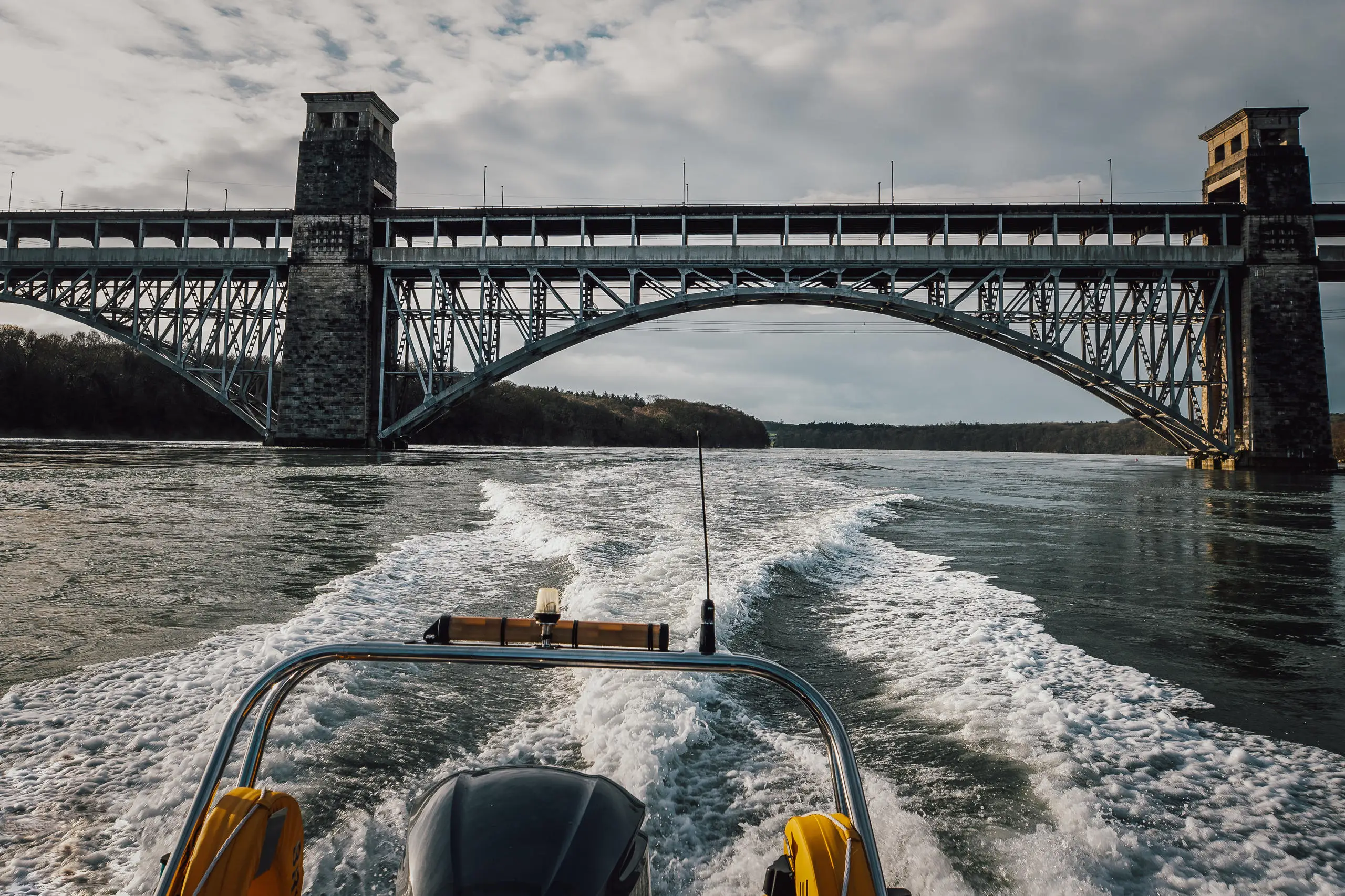 Raft of RIb going under Brittania Bridge showing the wake behind