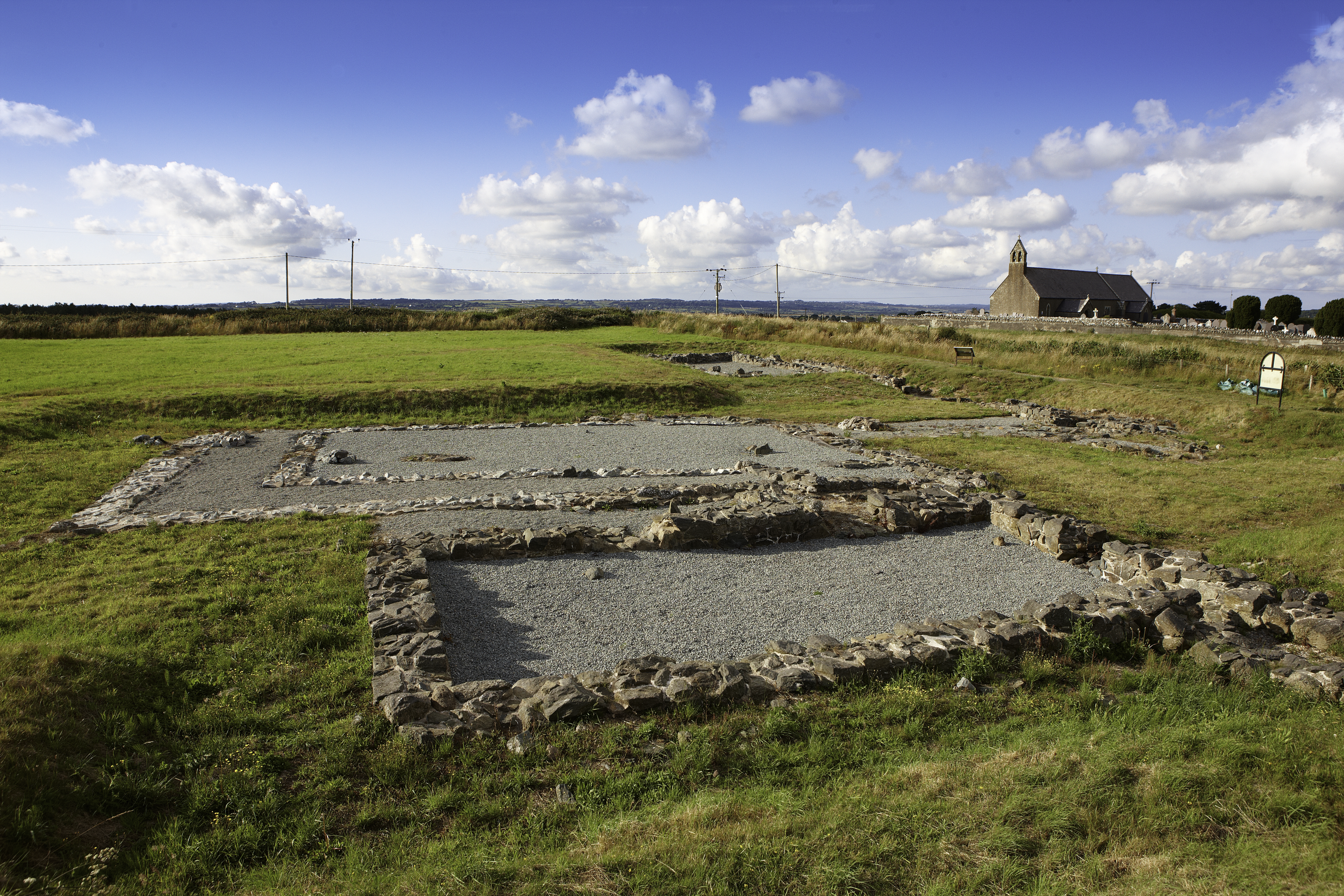 Remains of Llys Rhosyr showing the footprint of the old court with farm house in the distance