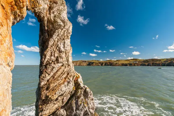 White rock arch at Porthwen looking across the bay to Bull Bay and white house on the headland