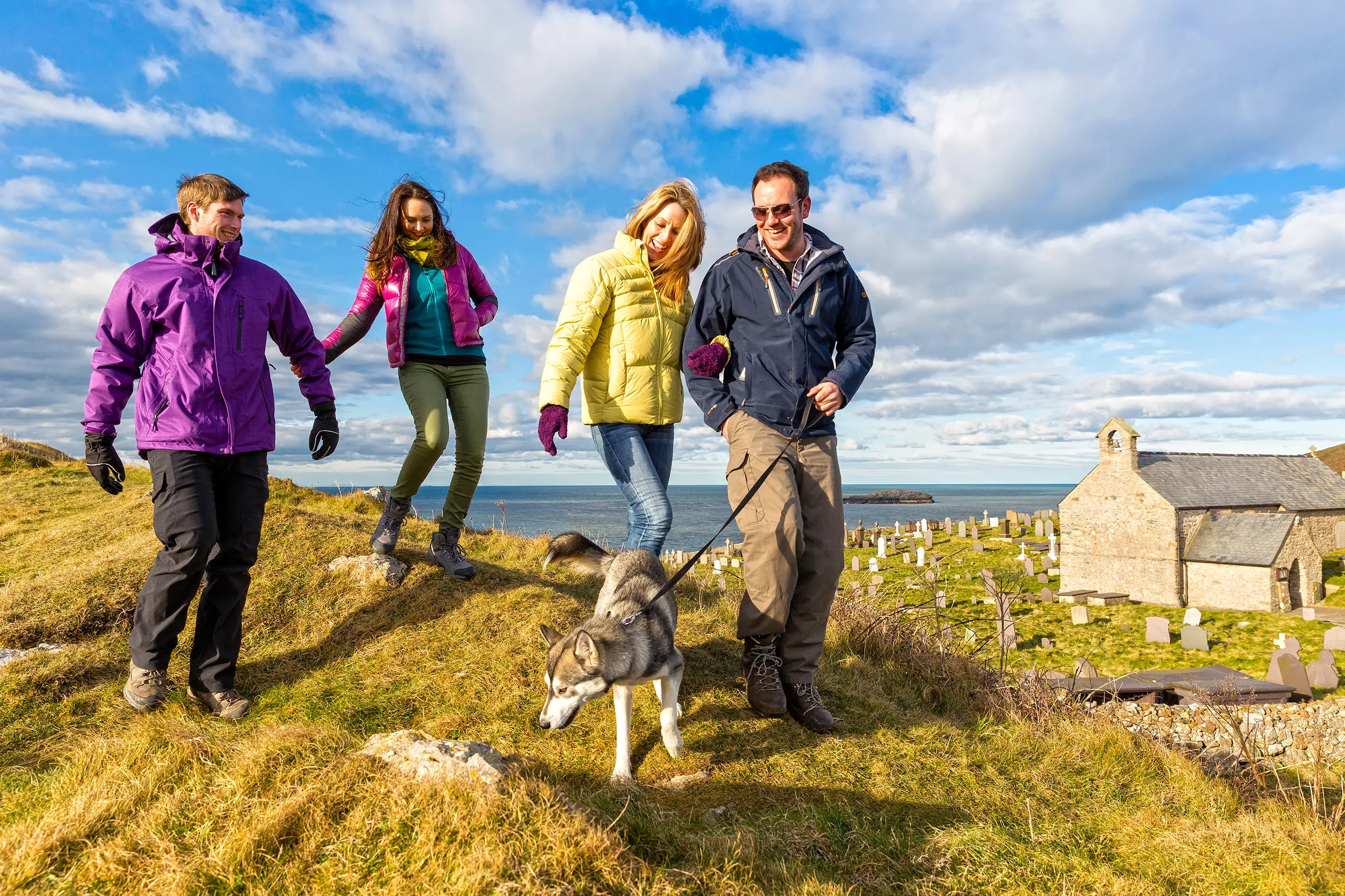 Four walkers and their dog with St Patricks church behind and views to the Irish sea