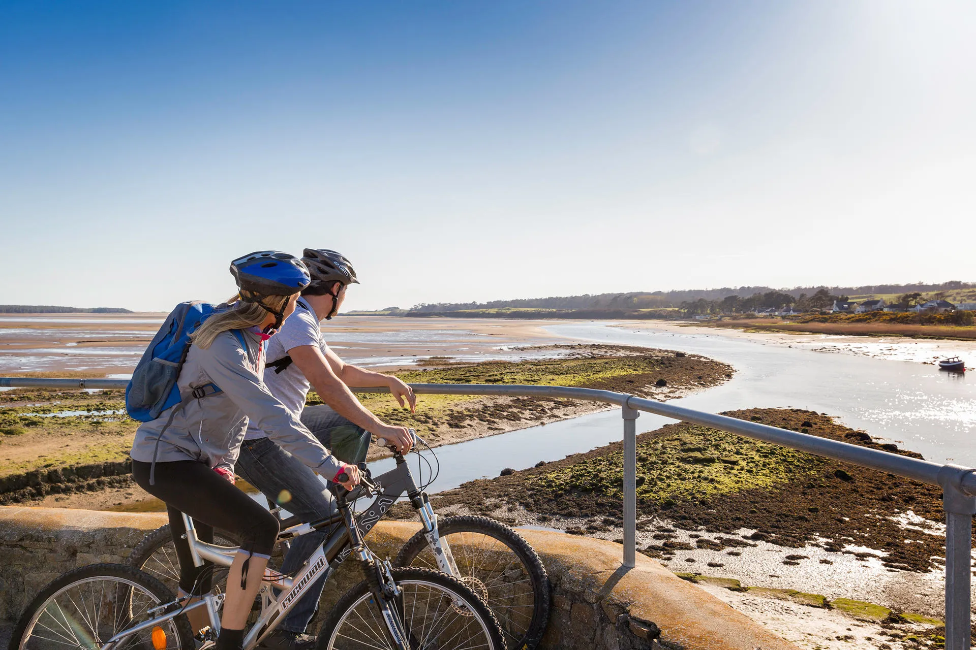 Two cyclists on the bridge at Malltraeth looking out to sea with the tide out next stop Venezuela 