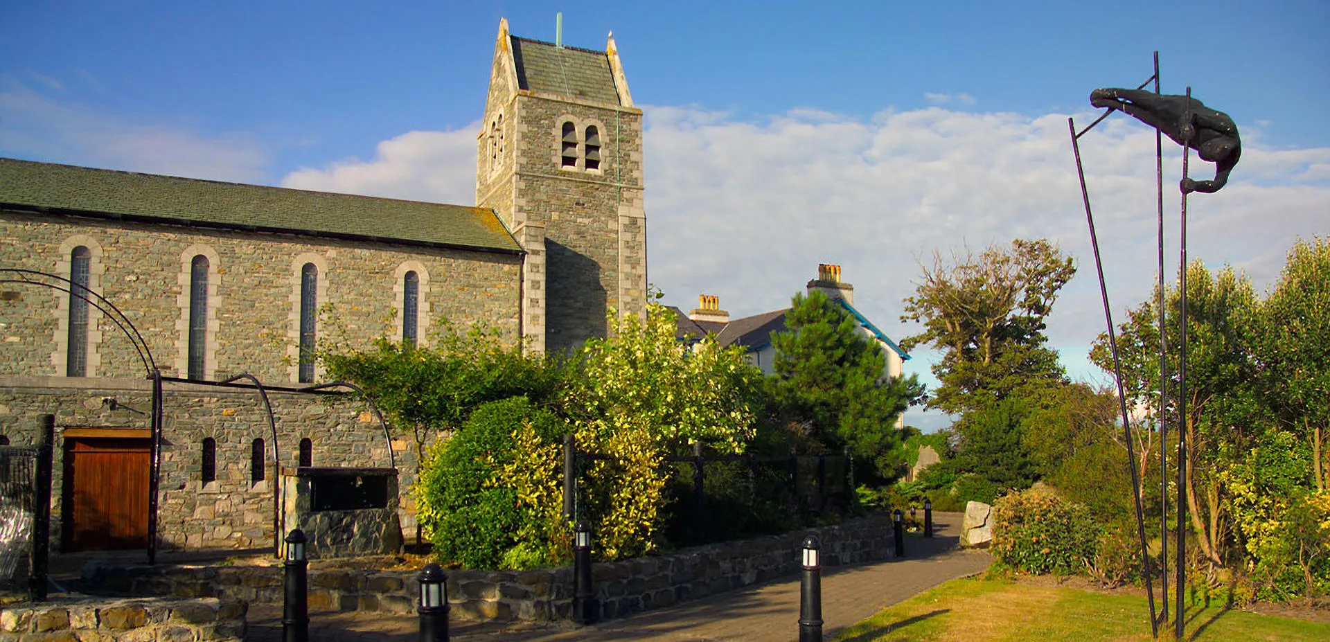 The tower at the Ucheldre Centre surrounded by green trees and art sculptures