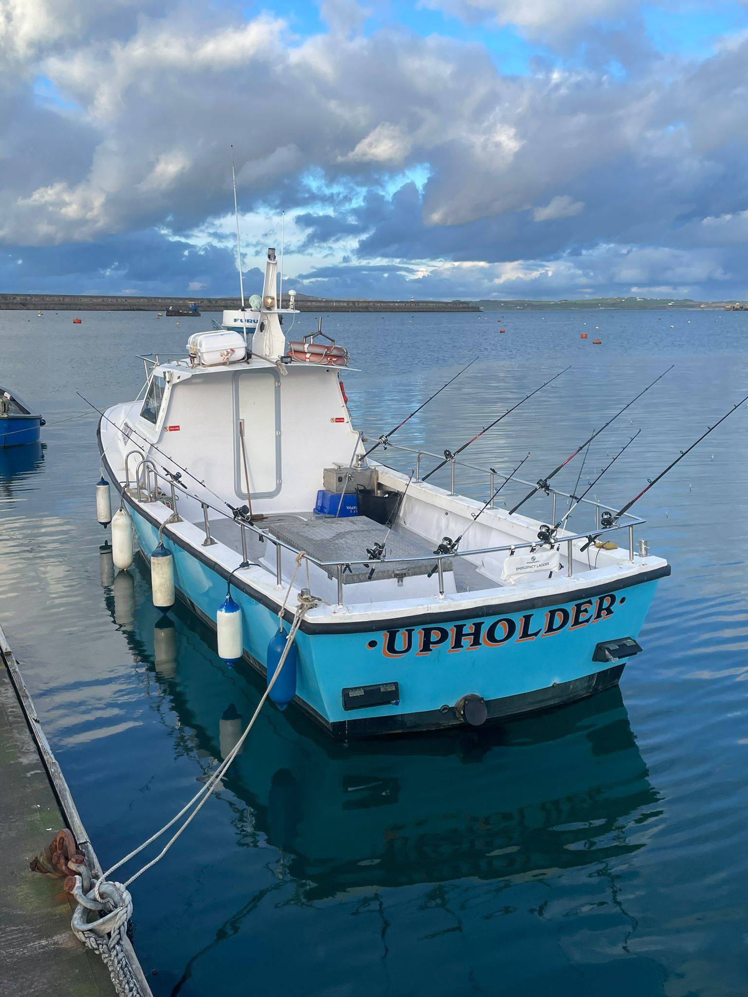 White and blue fishing boat 'Upholder' moored in a harbour