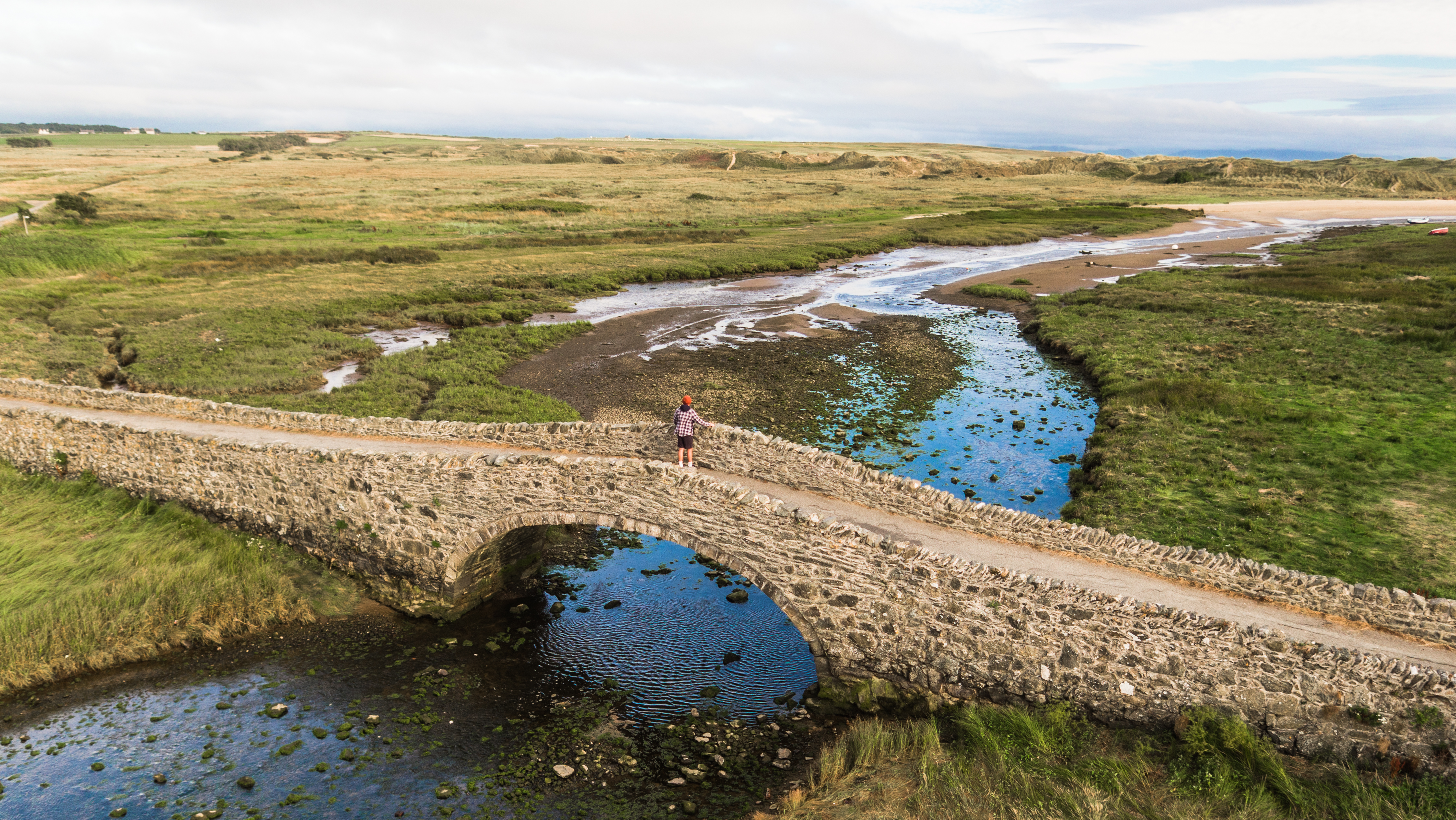 Aberffraw bridge looking out towards the sand dunes with low tide with cirrostratus clouds forming on the right