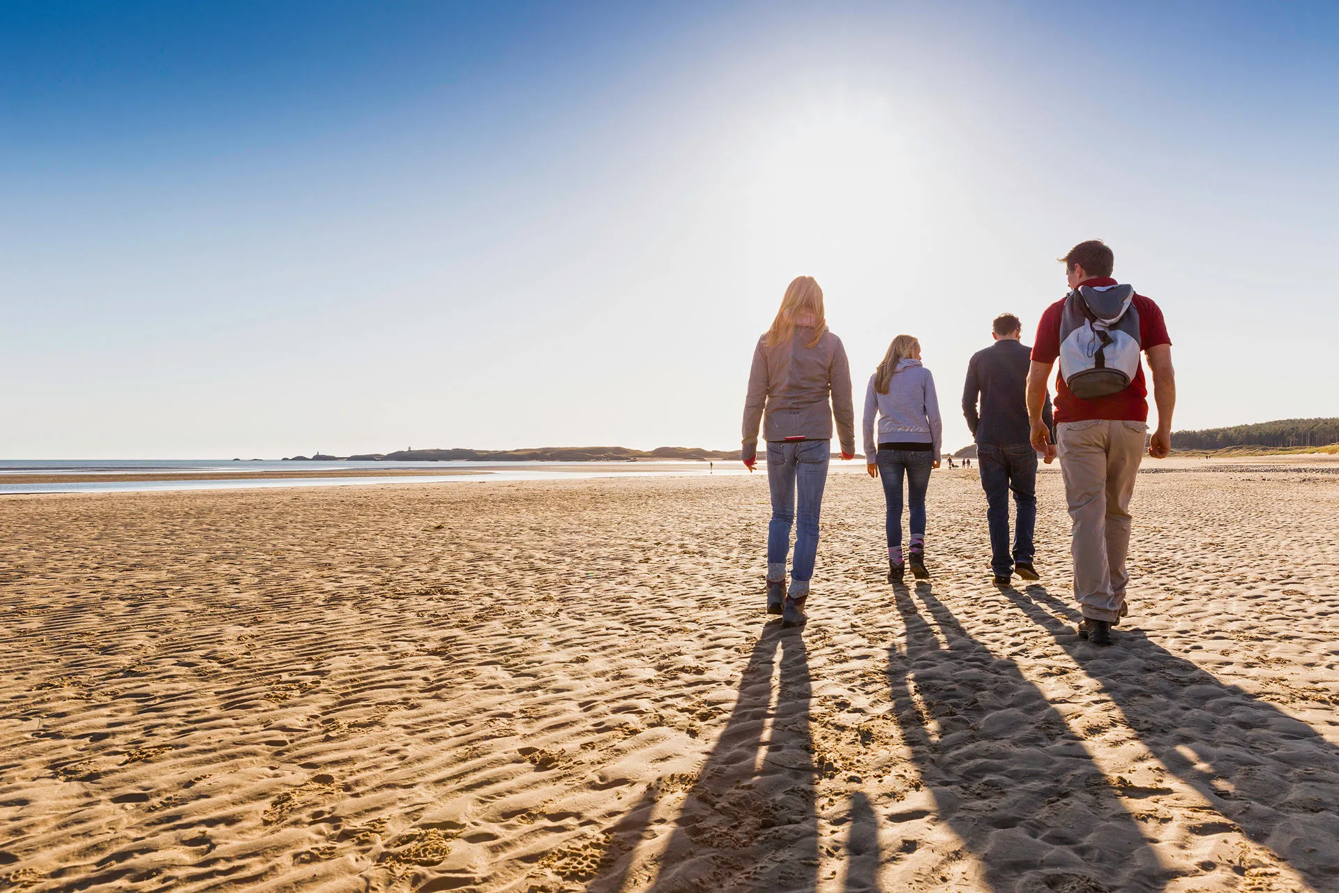 Family walking on beach with sun above