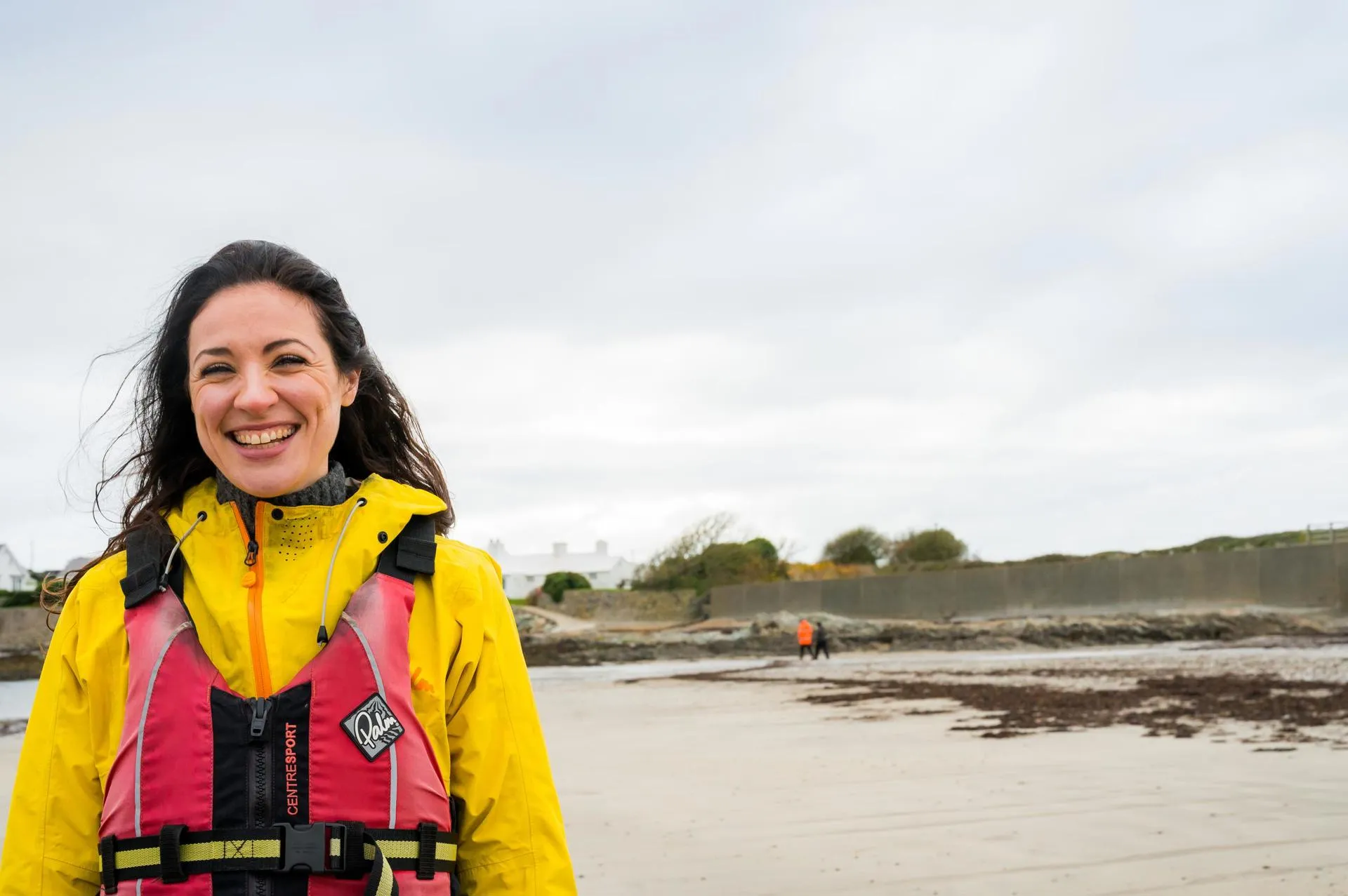Woman in sailing gear on Rhoscolyn beach
