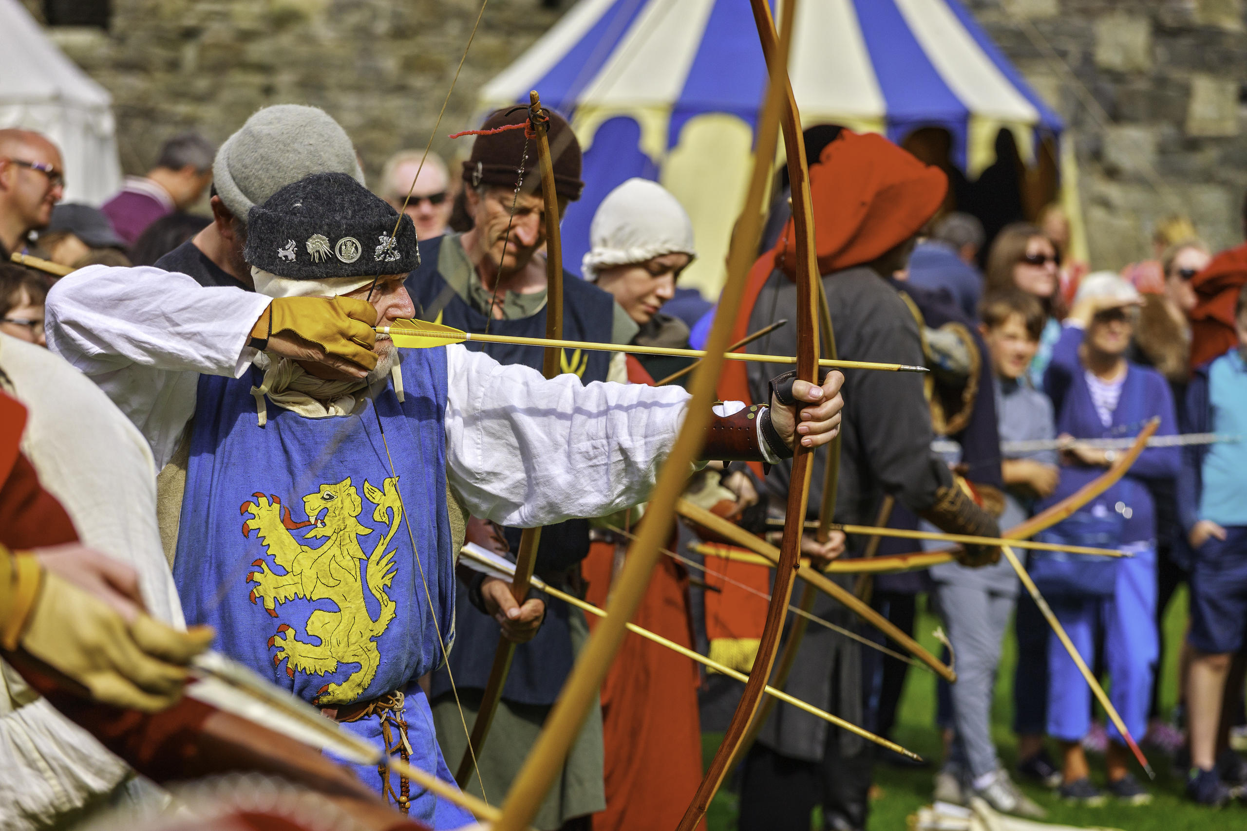 medieval archers taking aim with traditional long bows within Beaumaris castle.