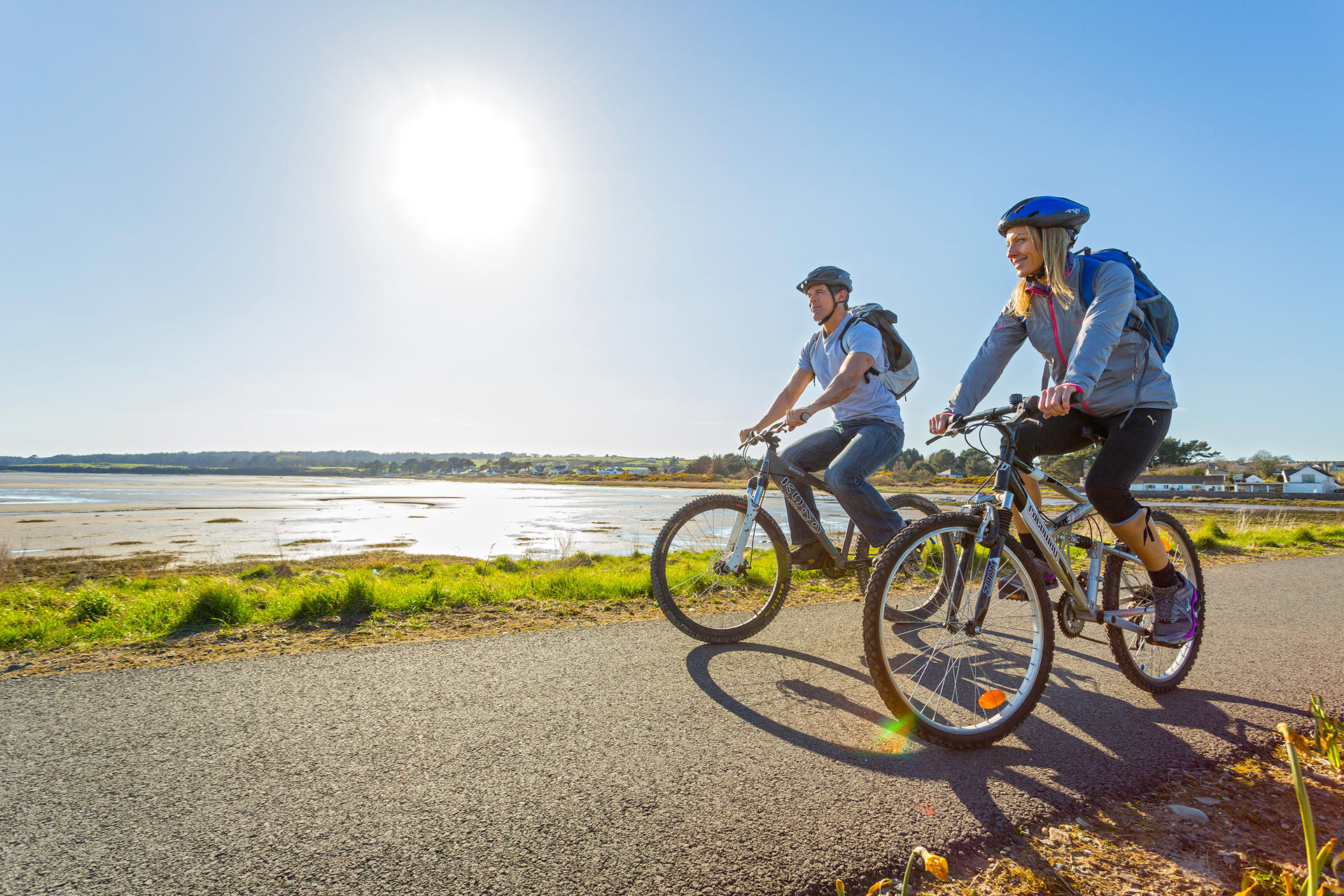 Couple cycling alongside each other in the sunlight