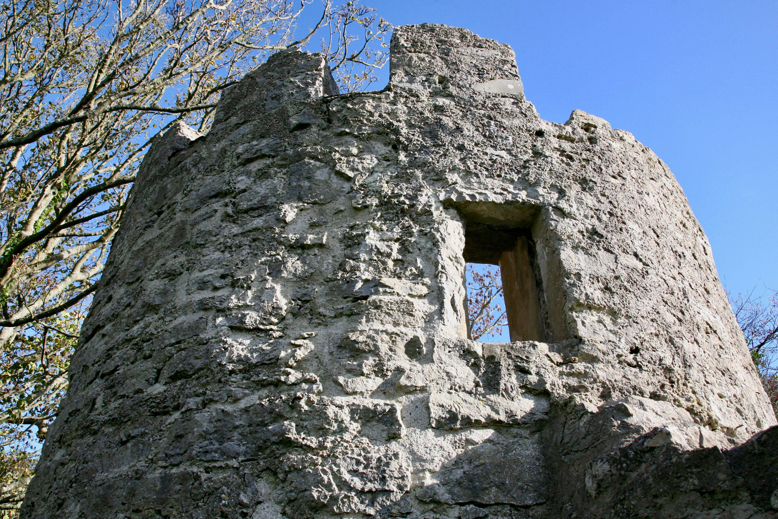 One of the towers at Aberlleiniog mott and bailey Castle with window opening and turrets and blue sky above 