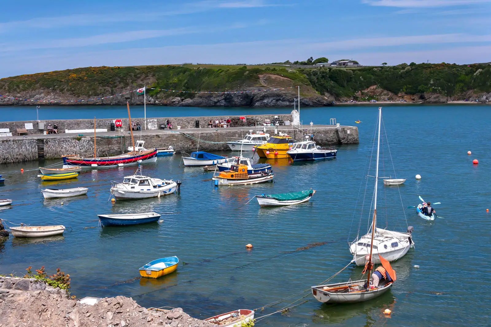 Cychod yn harbwr Cemaes gyda'r morglawdd yn y cefndir