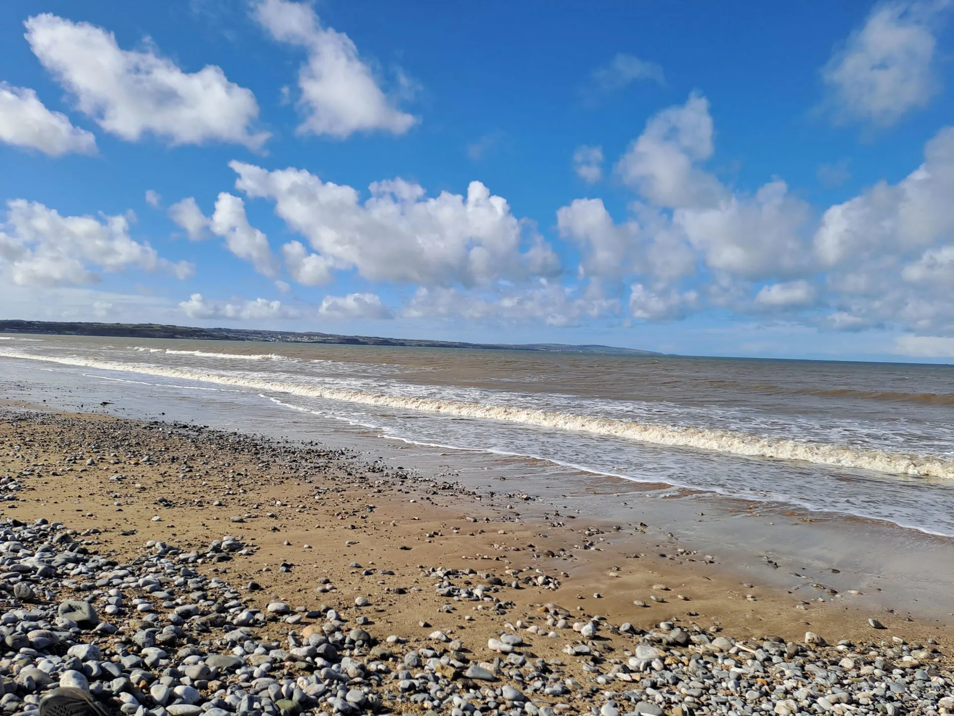 View looking out to sea with rolling waves and pebbles under foot