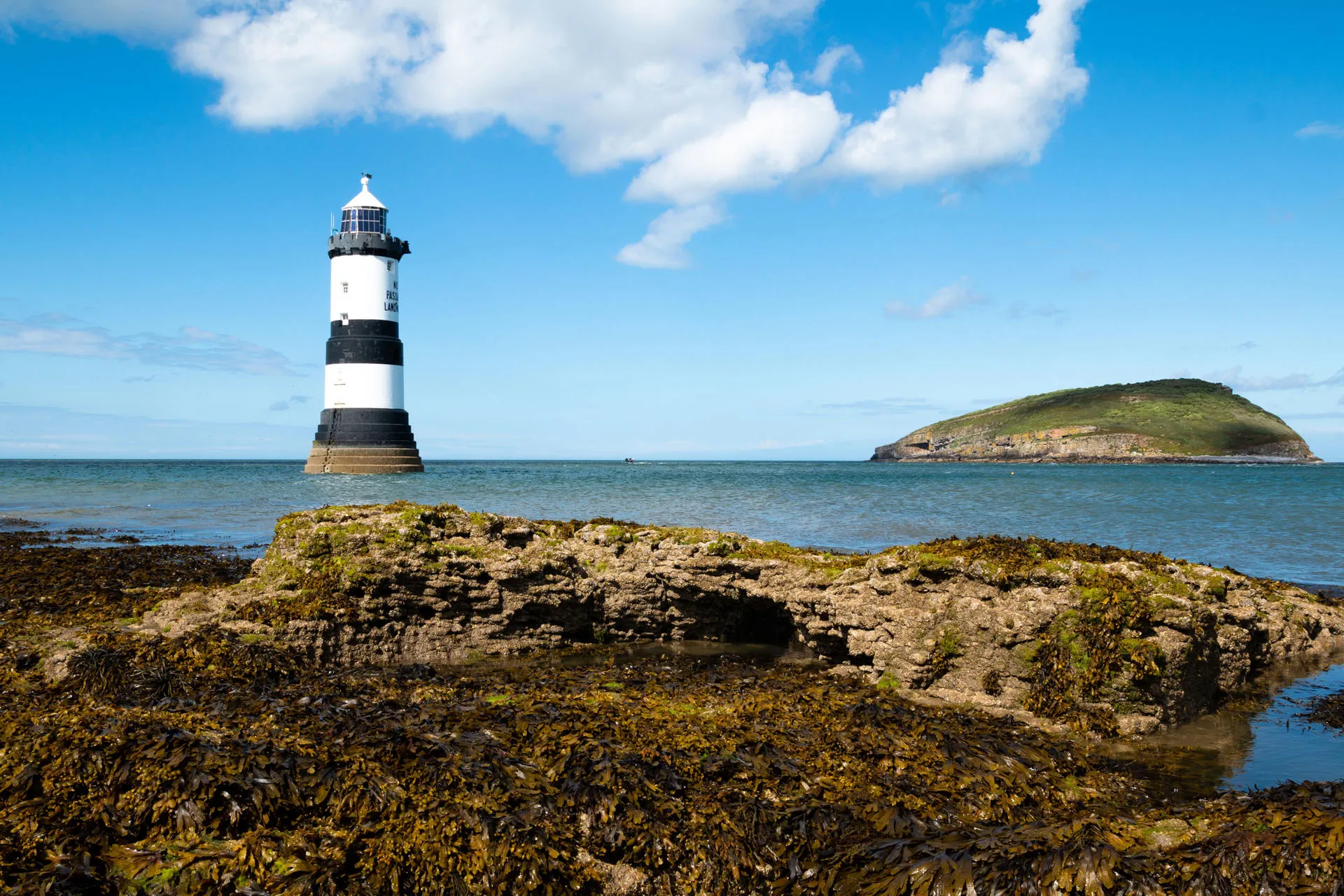 Penmon lighthouse surrounded by the sea with Puffin island in the distance
