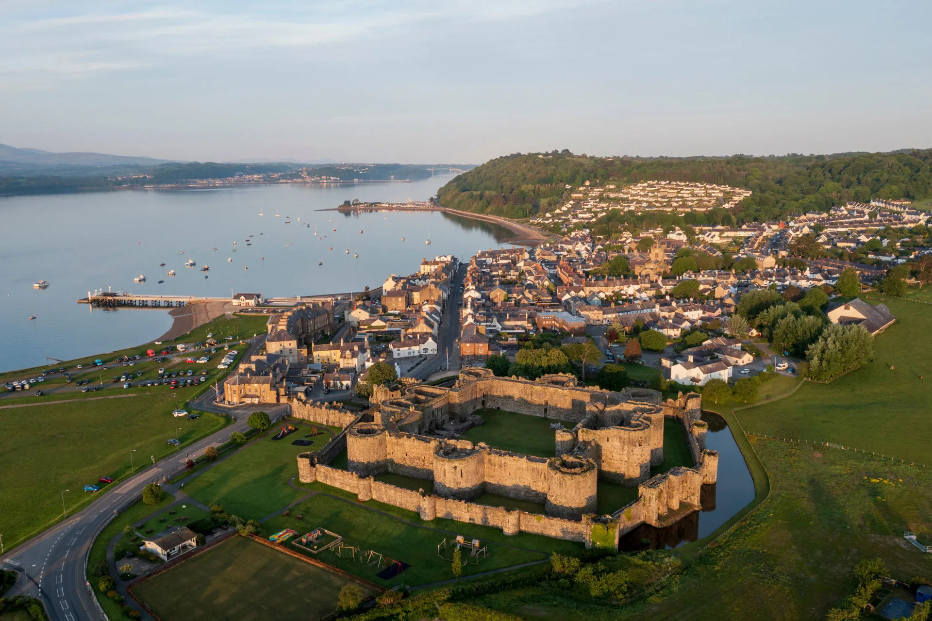 Aerial view of Beaumaris Castle at dawn with the seaside town beyond