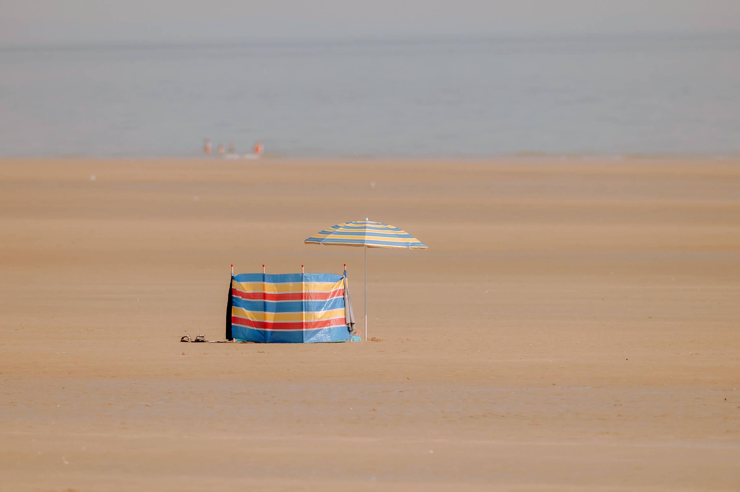 A wind break and umbrella on an empty beach
